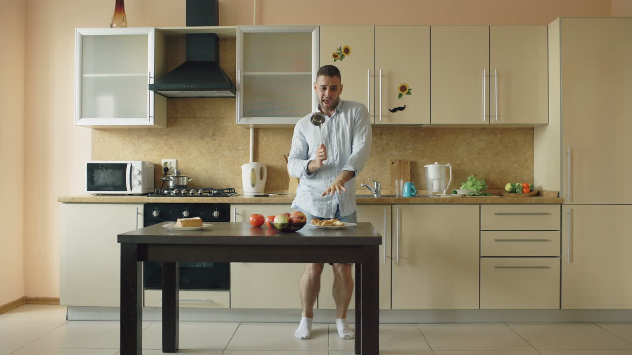 Mutfakta mutfak gereçleriyle dans eden adam