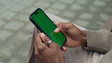 person holding a smartphone with a green screen