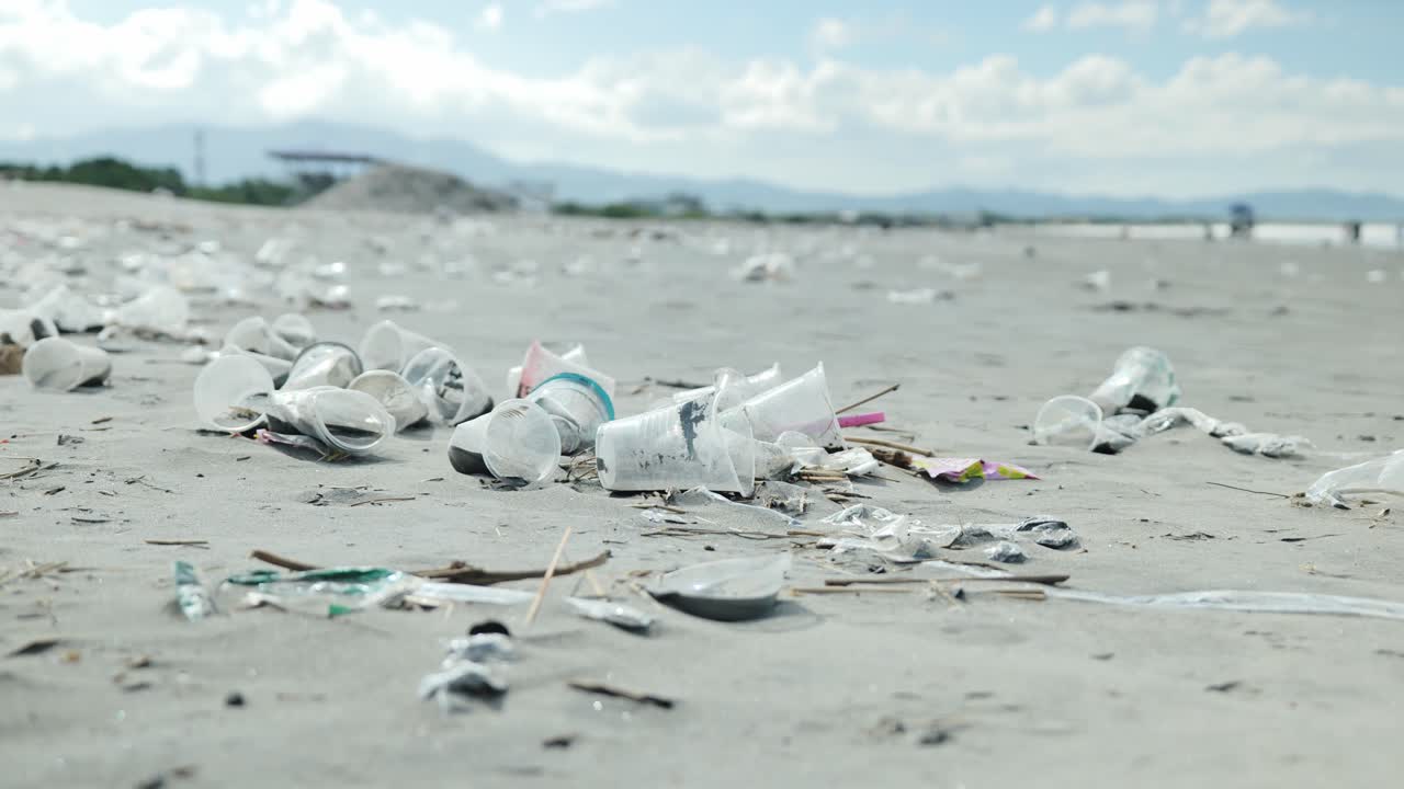 I rifiuti di plastica coprono la costa di Lingayen mentre un vento leggero sposta i detriti sotto cieli grigi.
