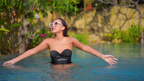 Sesión-De-Moda,-Sexy-Mujer-Exótica-Rociando-Agua-En-La-Piscina-En-Un-Día-Soleado-En-Un-Destino-Tropical,-Fotograma-Completo-En-Cámara-Lenta