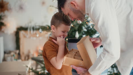 father and young son unpacking old christmas decorations and decorating tree