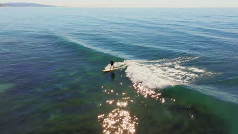 surfer riding blue ocean wave in san diego, california, usa - aerial drone shot