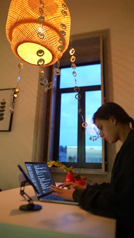 mujer trabajando en una computadora portátil en casa por la noche