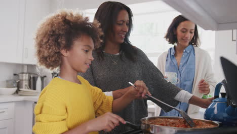 Pre-teen-African-American-girl-cooking-food-in-the-kitchen-with-her-grandmother-and-mother,-close-up