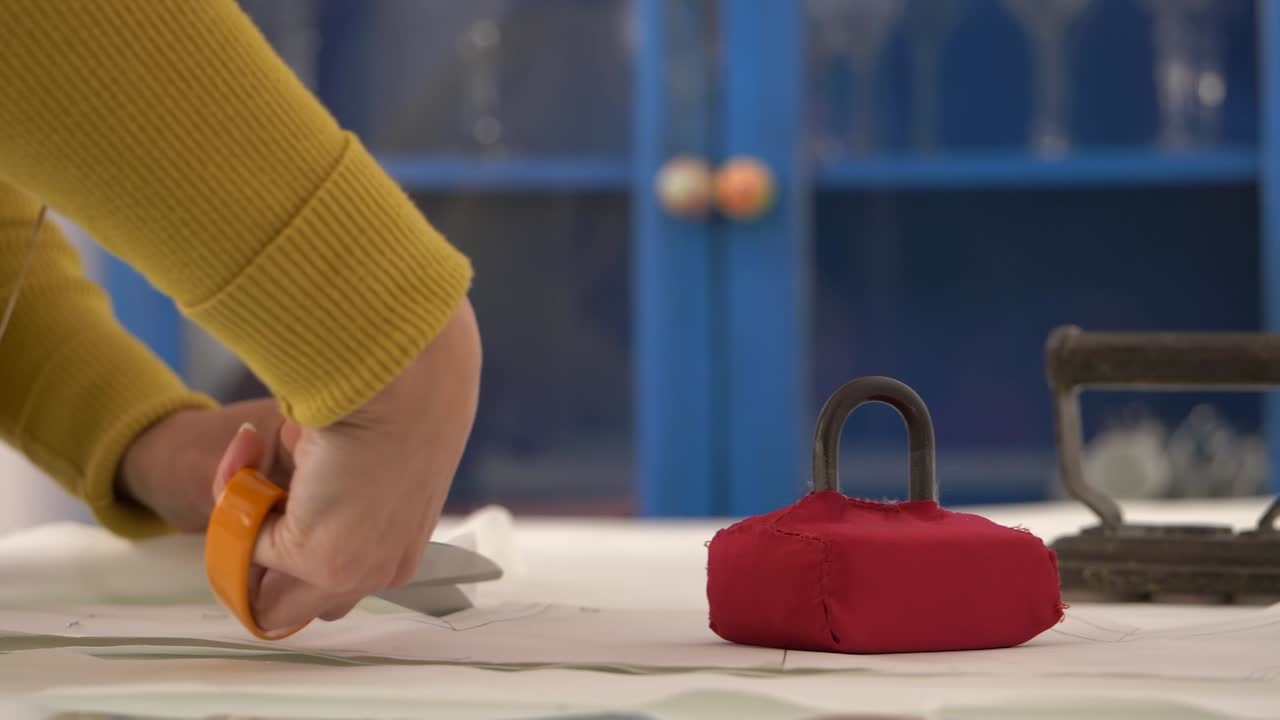 los pesos del patrón de costura mantienen la tela en su lugar mientras el sastre corta la tela, el control deslizante de cámara lenta