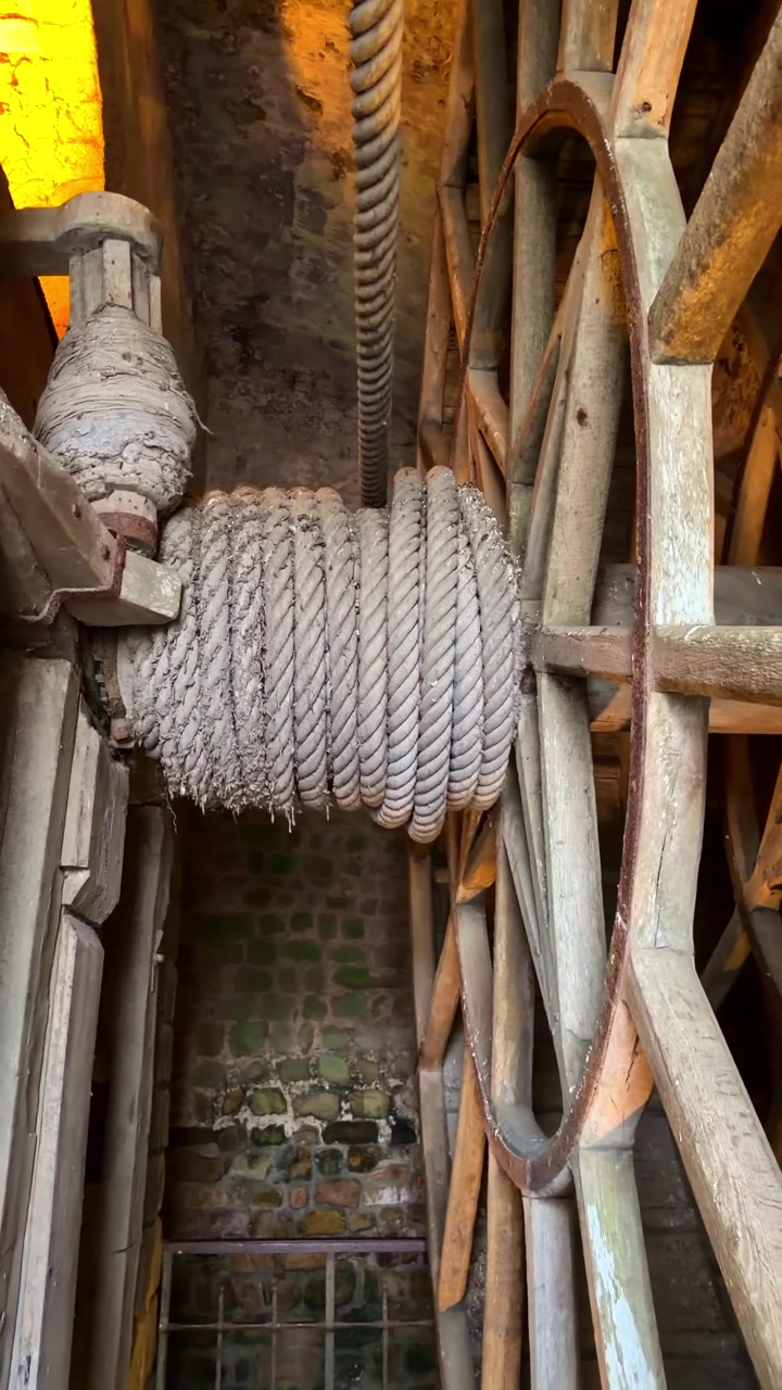 Ancient wooden treadwheel with thick coiled rope used to haul supplies up to Mont Saint-Michel Abbey, historic medieval hoisting mechanism in Normandy France