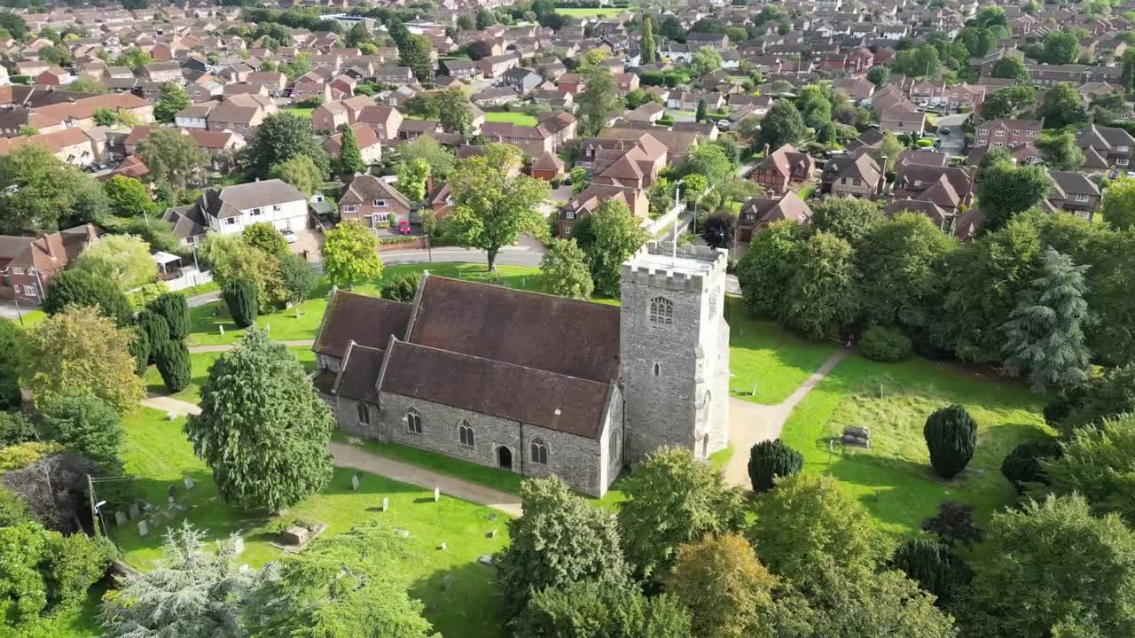 Drone orbit video showing St Marys Church in Lyddington village Rutland England, featuring historic stone church, square tower, green graveyard, surrounding houses, and calm rural setting