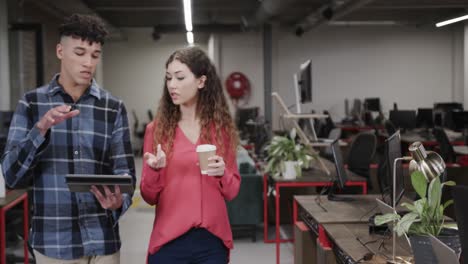 two diverse creative designers in discussion at tablet in casual office, slow motion