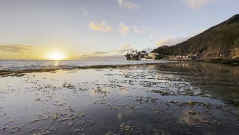 una fascinante puesta de sol sobre el océano, con la luz dorada reflejándose en la superficie del agua y la arena húmeda