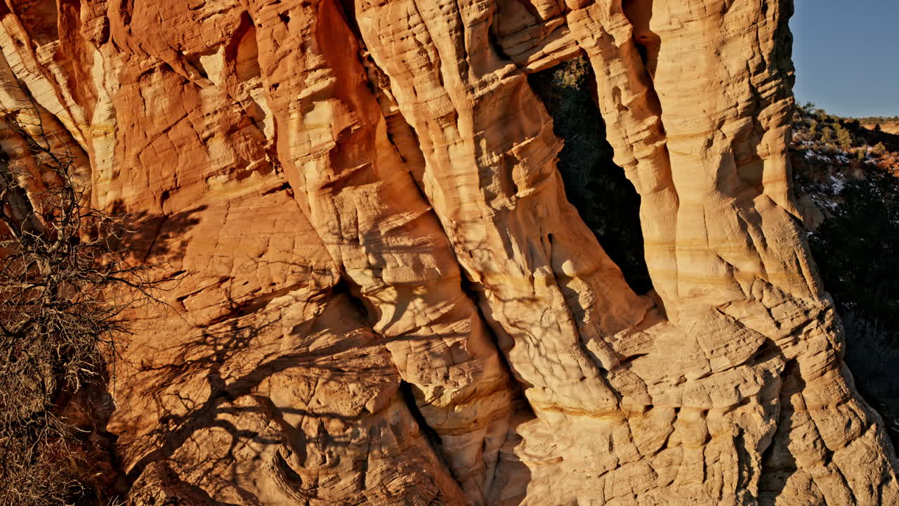 Soft morning light bathes a stunning rock arch in Utah’s desert, captured by drone.