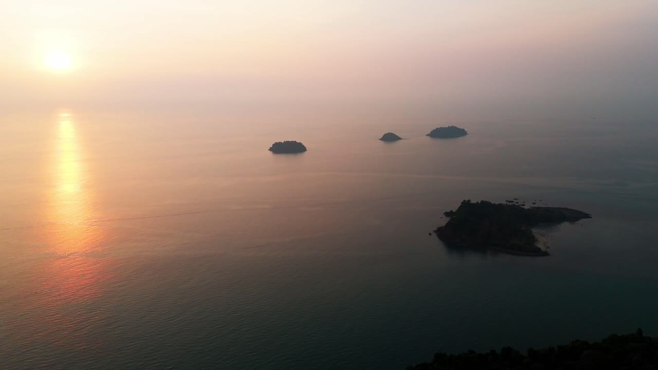 Aerial tracking right across Koh Chang islands at dusk, warm glow over the tranquil ocean waters