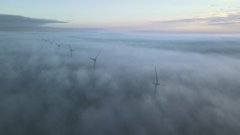 Toma-Aérea-Panorámica-Lateral-De-Aerogeneradores-Girando-En-Las-Nubes-En-Un-Amanecer-épico-Con-Nubes-Bajas