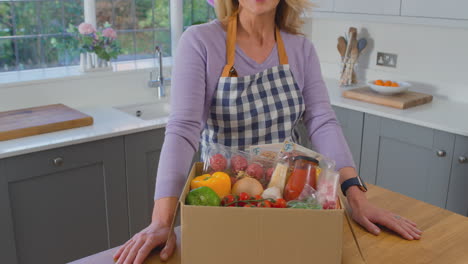 portrait of woman unpacking online meal food recipe kit delivered to home - shot in slow motion