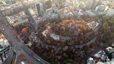 Aerial-orbit-of-Santa-Lucia-Hill-with-autumnal-trees,-Caupolican-Terrace,-between-Alameda-avenue-and-Santiago-buildings,-Chile