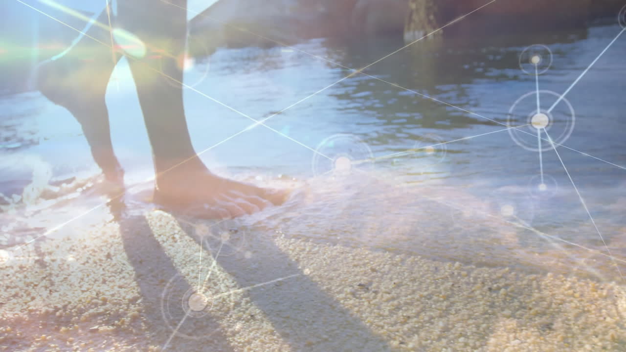 Bare feet walking on sandy beach with network connections animation overlay