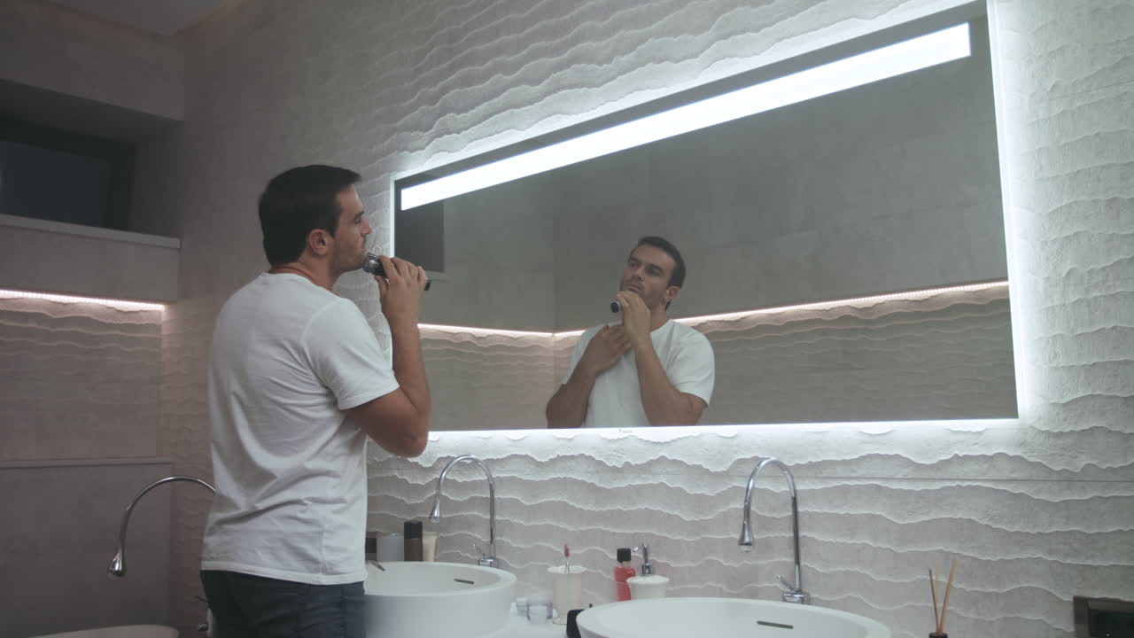 Uomo elegante che si rade la barba in un bagno di lusso. Un uomo concentrato si sta radendo in bagno.