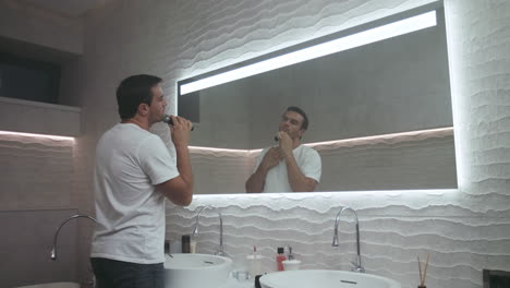 Handsome-man-shaving-beard-in-luxury-bath.-Concentrated-man-shaving-in-bathroom