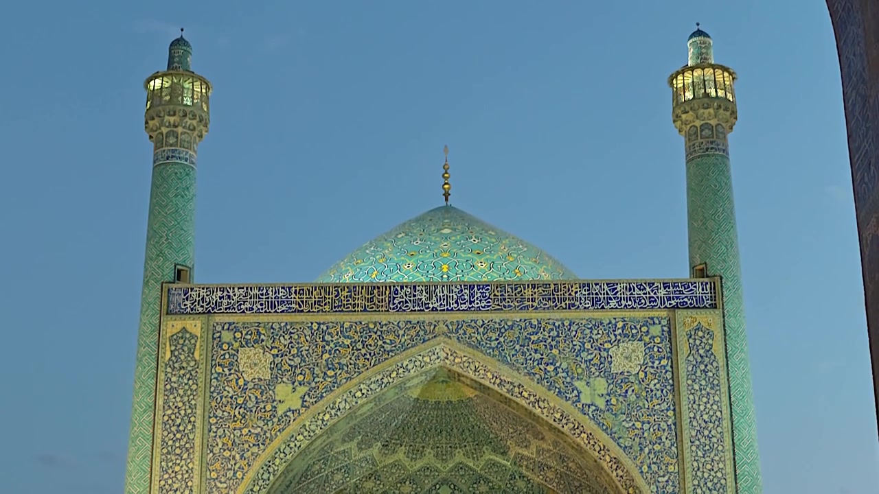 Oplyst indgang og minareter til en traditionel persisk moské i skumringen