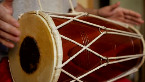 close up of hands of a man playing a drum.