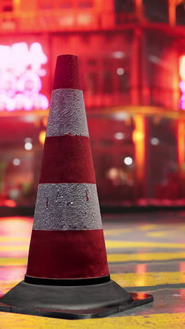 a red and white traffic cone on a city street at night