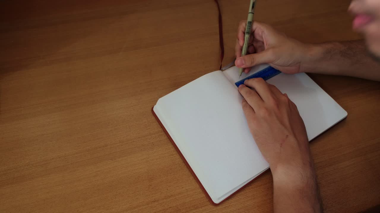 Opening journal notebook and writing lines with a small ruler and pen for layouting - static medium shot