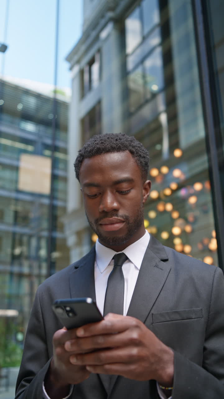 Vertical Video Shot Of Young Businessman Wearing Suit Using Mobile Phone Standing Outside Offices In The Financial District Of The City Of London UK Shot In Real Time 2