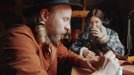 Man-Smoking-Cigarette-and-His-Wife-Drinking-Tea-in-Craft-Workshop