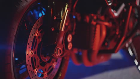 close-up of a motorcycle wheel and brake components at night with colored lights