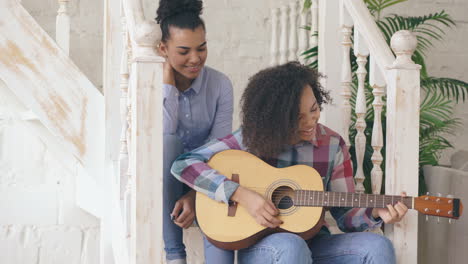 two girls playing guitar on staircase