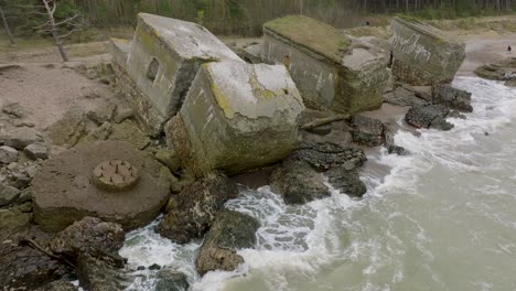 hermosa vista aérea de los edificios de fortificación costeros abandonados en los fuertes del norte de karosta, costa del mar báltico, grandes olas, día nublado, cámara lenta, disparo de drones moviéndose hacia atrás