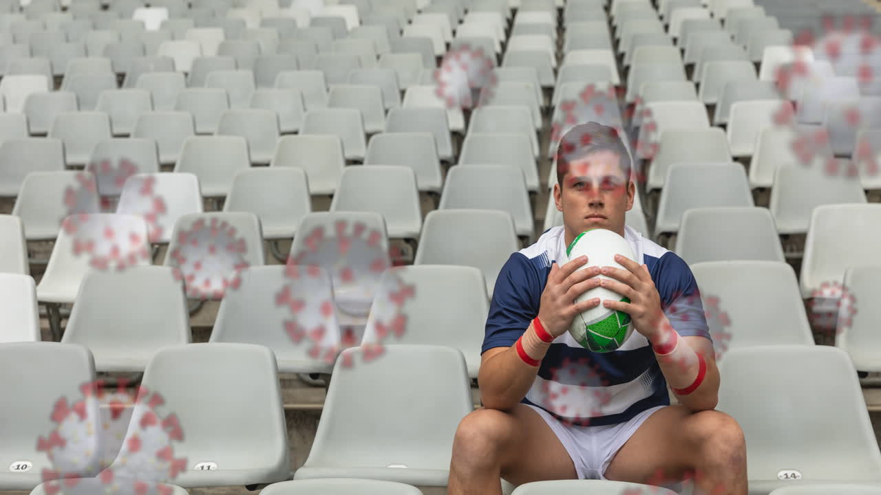 células covid-19 contra el jugador de rugby masculino con una pelota de rugby y sentado en las gradas del estadio