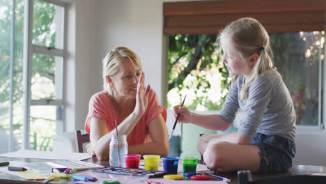 Vista-Lateral-De-Una-Mujer-Caucásica-Pintando-Con-Su-Hija-En-Casa-Y-Chocando-Esos-Cinco