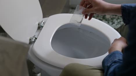 Male-pouring-white-powder-narcotics-drug-substance-in-plastic-zip-lock-back-down-toilet