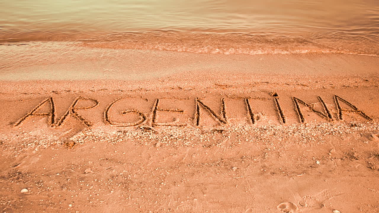 Inskriptionen 'Argentina' i sanden. Inskription på sand, stranden.