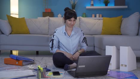una trabajadora de oficina en casa aplaudiendo lo que ve en la computadora portátil.