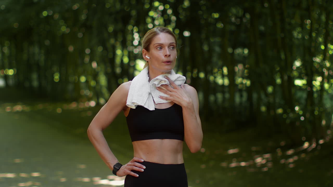 Woman wiping sweat with a towel after a workout in a park
