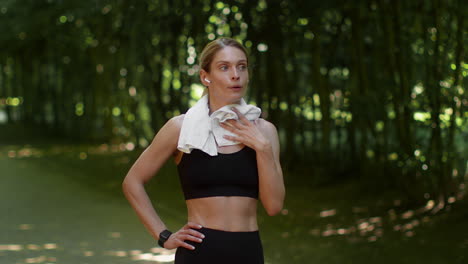 woman wiping sweat with a towel after a workout in a park