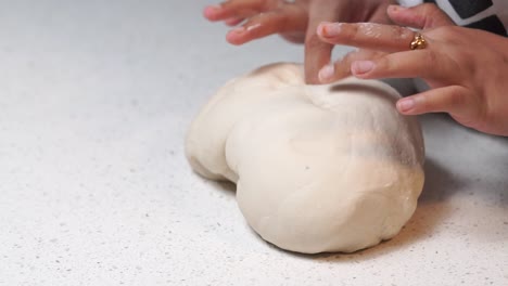 kneading white dough with hands on white table slow motion