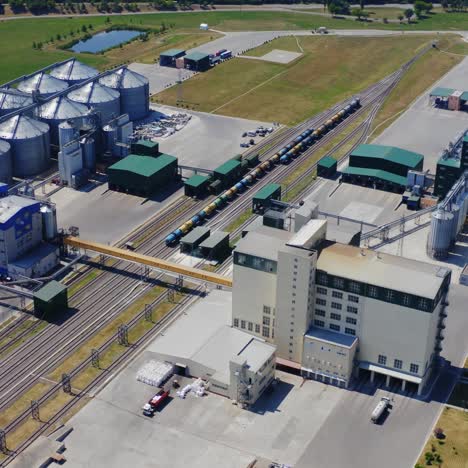 contemporary industrial territory in the countryside. exterior of silver containers for storing cereals. freight wagons of train on industrial zone. aerial view.