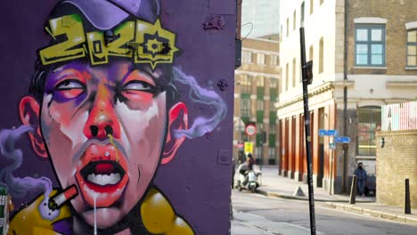 Street-art-in-Brick-Lane-in-London,-graffiti-of-a-frustrated-and-insane-man-with-fuming-ears-because-of-the-year-2020-and-Covid-19-Coronavirus-pandemic,-empty-street-during-lockdown