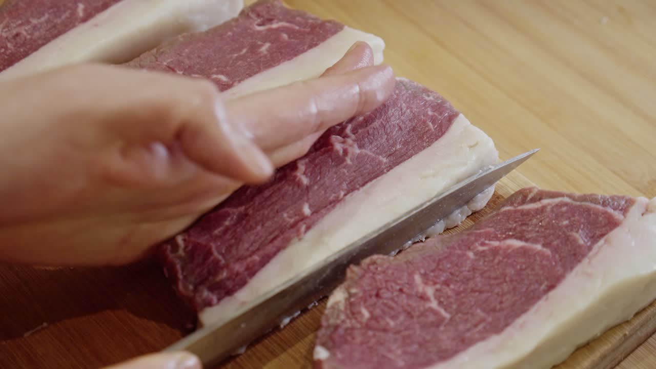 나무로 자른 판자에 스테이크를 만드는 요리사의 손에 가까이