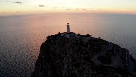 historic old lighthouse on the edge of cliff at sunset orange light shadows, drone aerial