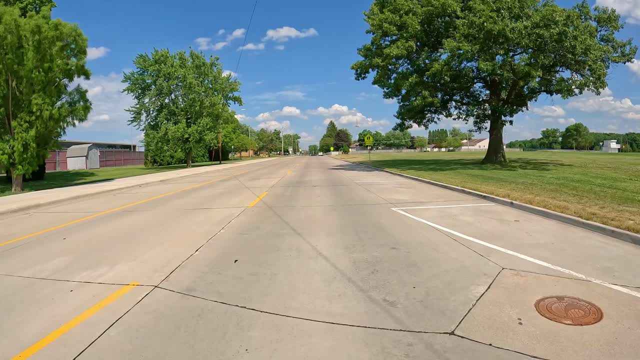 - pov conduciendo en la calle de la ciudad más allá de las cercas en las canchas de tenis y un campo de fútbol abierto en moline illinois