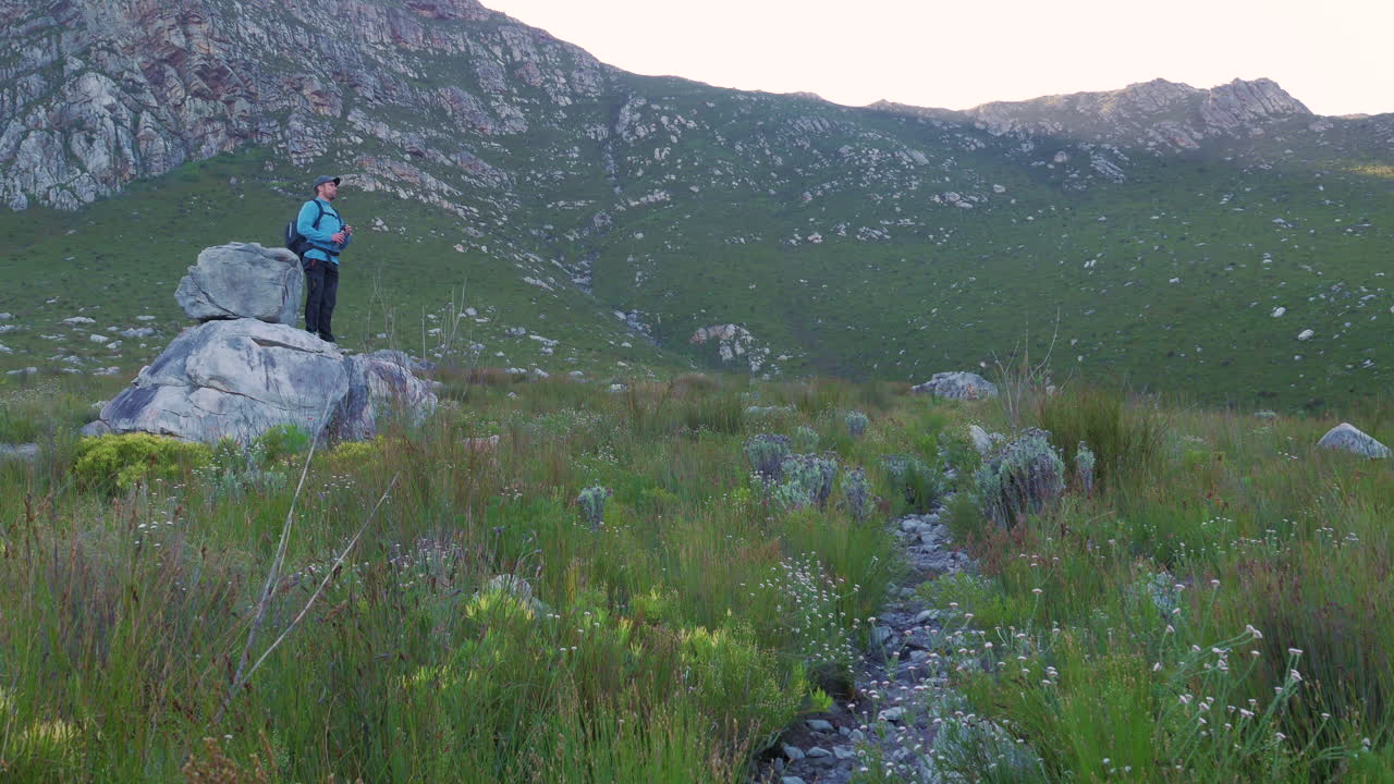 hombre en caminata, toma un descanso en el agua potable de roca con una enorme montaña de arenisca en el fondo