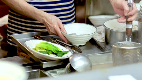 chef assembling noodle soup with fresh ingredients