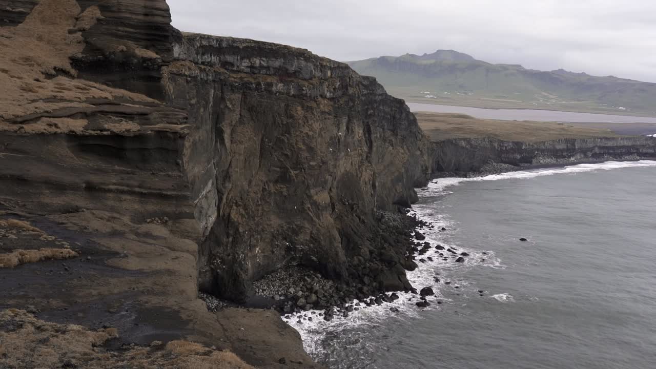 acantilado rocoso lavado por el mar espumoso en clima nublado