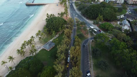 4k cinematic drone shot following our car as it drives next to waikiki beach and into queen kapi'olani park in oahu