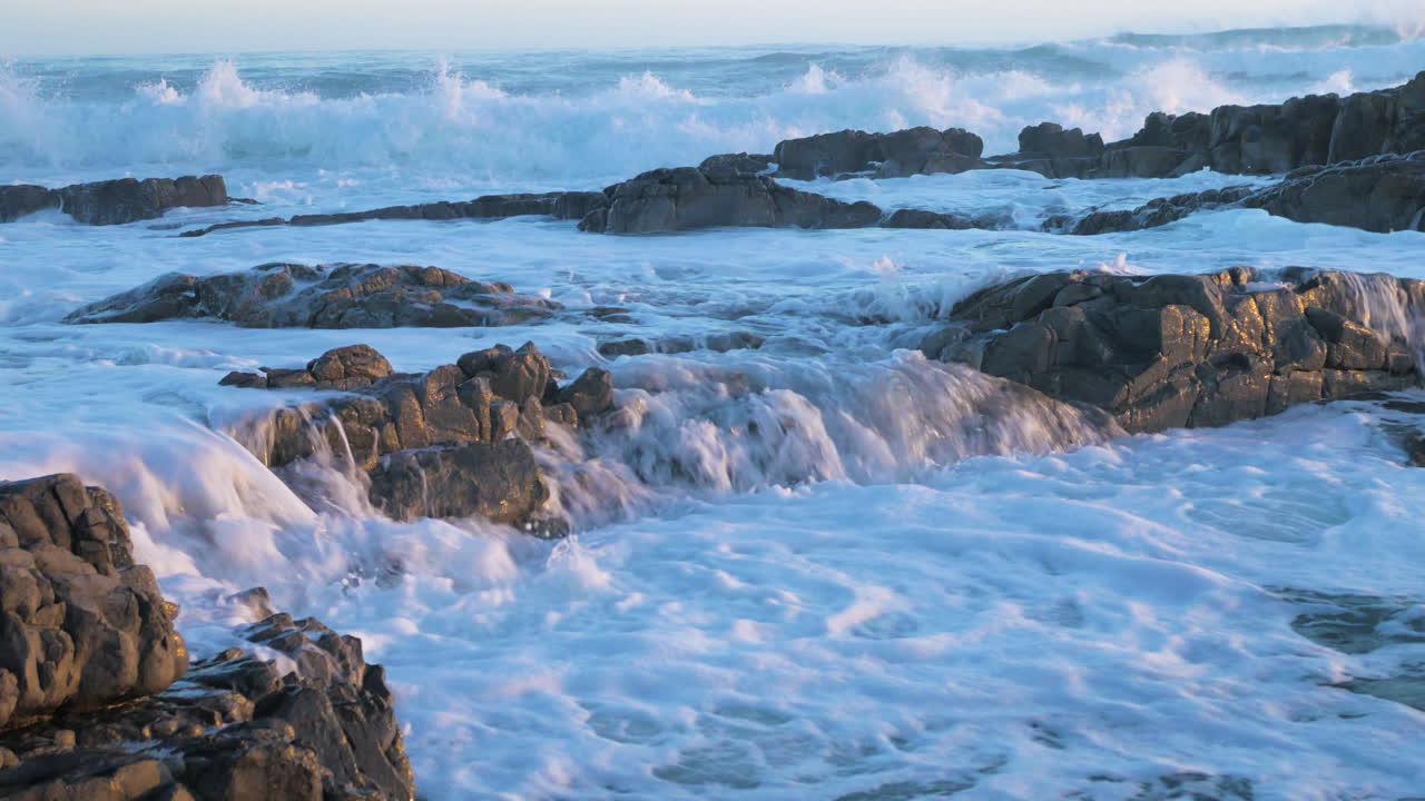 Onde che spingono l'acqua di mare che scorre sopra le rocce in un'altra pozza, primo piano