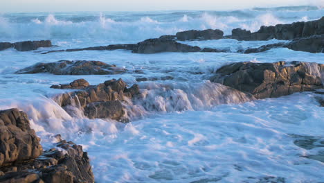 waves pushing flowing seawater over rocks into another pool, close-up