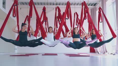 Damengruppe-Zeigt-Twine-Fly-Yoga-Pose-Mit-Langen-Hängematten